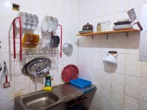 a kitchen with a sink and a shelf with dishes at Gadou Rooms -Private & Shared Stays in Port Said Best Location in Port Said