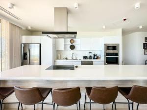 a kitchen with a large white counter and chairs at 5BR Beachfront Luxury Condo in Puerto Peñasco