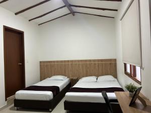 a bedroom with two beds and a desk and a table at Hotel Terraza in Buga