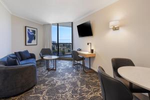 a living room with a couch and tables and chairs at Hotel Grand Chancellor Brisbane in Brisbane