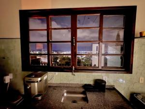 a window in a kitchen with a sink in front of it at Deck da colina in São Pedro da Aldeia +61 photos