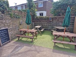 a group of picnic tables with umbrellas next to a wall at The Church House Inn in Bollington