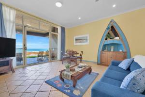 a living room with a blue couch and a table at Absolute Beachfront l Couples Getaway in Blue Bay 