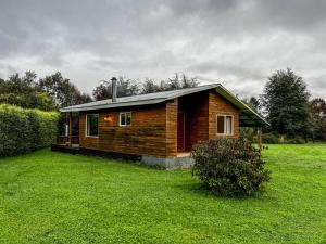 a small wooden cabin in a grassy field at Cabañas Tranquihue Llifen in llifen
