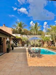 a patio with a table and chairs next to a pool at Chácara Renil in Olímpia