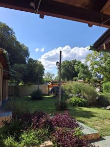a garden with purple flowers and a wooden pole at Cabañas del Molle in Valle Hermoso