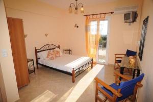 a bedroom with a bed and two chairs and a window at Sophi's L Studios & Apartments in Agia Anna Naxos