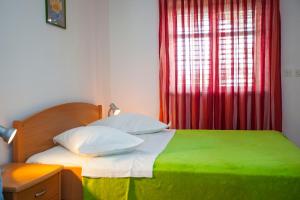 a bedroom with a green and white bed with a window at Studio Apartment Mrnjica in Brela