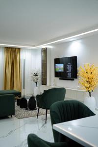sala de estar con sillas verdes y TV de pantalla plana en Nest Luxury Apartment, en Ilorin