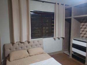a bedroom with a large bed and a window at Guest House in Uberlândia
