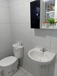 a white bathroom with a toilet and a sink at Encantos do Natal em Garanhuns in Garanhuns