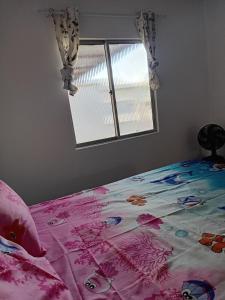 a bedroom with a bed with a pink blanket and a window at Encantos do Natal em Garanhuns in Garanhuns