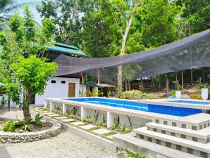 a swimming pool with a hammock in a garden at Molinillo Vacation Cabin in Ginatilan