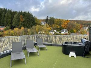 un patio con tre sedie e una vasca sul tetto di Holiday Home in Ardennes near Coo Waterfalls a Trois-Ponts