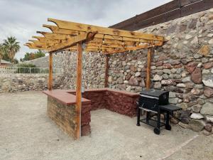 une pergola en bois avec une grille devant un mur en pierre dans l'établissement Peaceful West: 4BR Dusk Haven, à El Paso