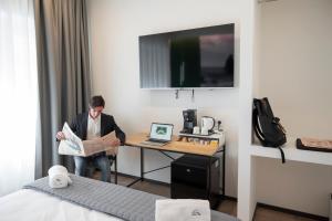 a man is standing at a desk in a hotel room at LN 5 Gate-Corso Italia in Catania