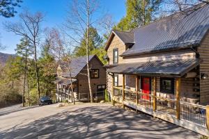 ein Blockhaus mit einer roten Tür und einer Einfahrt in der Unterkunft New Luxury Vacation Home Cabin in Smoky Gatlinburg - Theater Room in Gatlinburg