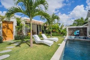 een achtertuin met een zwembad, twee witte stoelen en een palmboom bij NEW! Tropical Palms Villa - 4BR Villa in Kerobokan in Kerobokan