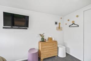 a living room with a tv on a white wall at Cozy cabin near adventure spots! in Rotorua