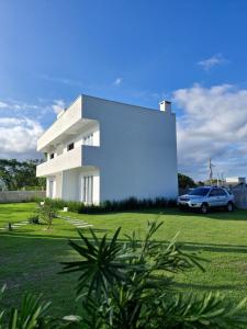 a white house with a car parked in front of it at Palo Santo - Praia do Rosa in Praia do Rosa
