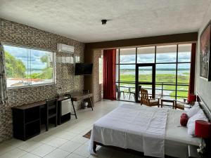 a bedroom with a bed and a desk and windows at La Posada del Cauchero Hotel & Suites in Iquitos