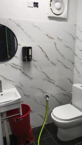 a bathroom with a toilet and a green hose at KAMI roomstay in Guar Chempedak +14 photos