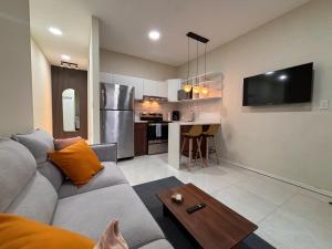 a living room with a gray couch and a kitchen at Apartment in the heart of SA in Santa Ana +9 photos