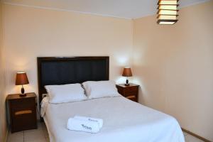 a bedroom with a large white bed with two night stands at Cabañas Rey Pacific in La Serena +9 photos