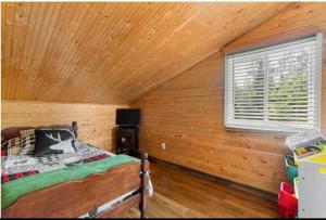 Un dormitorio con techo de madera con una cama y una ventana. en Chalet Domaine du Lac, en  Notre-Dame de Montauban 6 fotos más