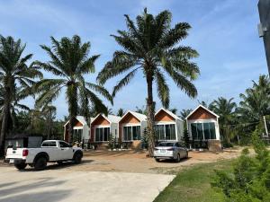 a row of houses with palm trees and a truck at Huather villa & cafe หัวเท่อวิลล่า in Ban Hin Sam Kon