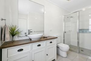 une salle de bain blanche avec lavabo et douche dans l'établissement Riverbank Cottage & Studio, à Shoalhaven Heads 9 autres photos