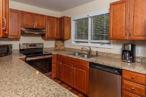 a kitchen with wooden cabinets and a stainless steel appliance at Sandpiper Court 14 by Wild Dunes, with Amenities in Isle of Palms