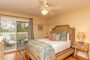 a bedroom with a bed with a ceiling fan and a balcony at Sandpiper Court 14 by Wild Dunes, with Amenities in Isle of Palms