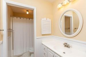a white bathroom with a sink and a mirror at Sandpiper Court 14 by Wild Dunes, with Amenities in Isle of Palms