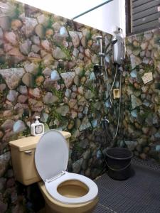 a bathroom with a toilet and a rock wall at HOST HOMES - CASA ELIZA in Tacloban +52 photos