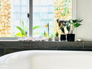 a white bath tub in a bathroom with plants at ヴィラパーム in Miyako-jima +50 photos