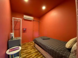 a bedroom with orange walls and a bed and a table at Simple Garden Restaurant and Resort in Baan Tai