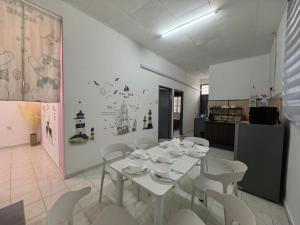 a dining room with a white table and white chairs at Padang Serai Harmoni Homestay in Padang Serai