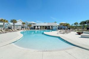 a large swimming pool with tables and chairs in a resort at Salty Shells - Spacious 3 Bedroom, 4 Bathroom Retreat in Orange Beach Just Steps from the Sand in Orange Beach