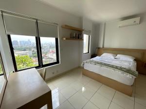 a bedroom with a bed and two large windows at Cosmo Park Town House in Jakarta