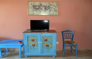 a blue cabinet with a tv and a chair at Polytropon Apartments in Kástron