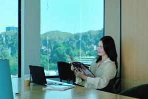 a woman sitting at a table with a laptop at Cicilia City Hotel Saigon Center in Ho Chi Minh City