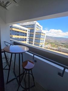 a balcony with two stools and a table and a window at Apartment in Torre Artemisa in Tegucigalpa