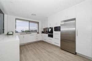 a kitchen with white cabinets and a stainless steel refrigerator at Bay Royal Apartments in Byron Bay