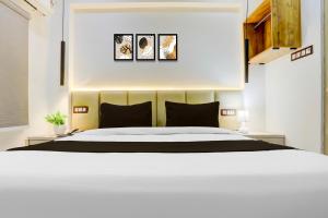 ein Schlafzimmer mit einem weißen Bett und drei Bildern an der Wand in der Unterkunft Collection O George Town in Colonelganj