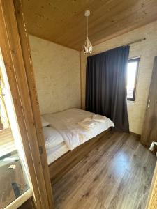 a small bed in a room with a window at Emerald Bazaleti in Dushetʼi