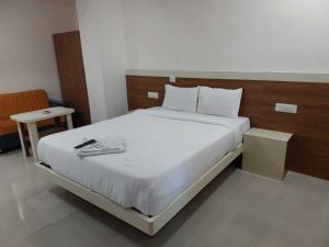 a bedroom with a white bed with a wooden headboard at Hotel O The Classic Crown in Pune
