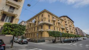 a large yellow building with cars parked in front of it at Edward House in La Spezia