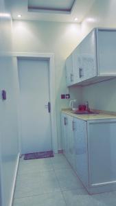 eine weiße Küche mit einem Waschbecken und einer Tür in der Unterkunft استديو هادئ النرجس in Quai