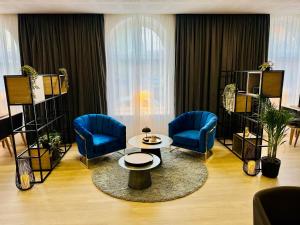 a living room with blue chairs and a table at DORMERO Hotel Wilhelmshaven in Wilhelmshaven